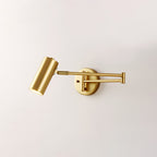 Clérachic gold wall light with its head tilted down, on a plain pale wall, with the arm folded at the elbow.
