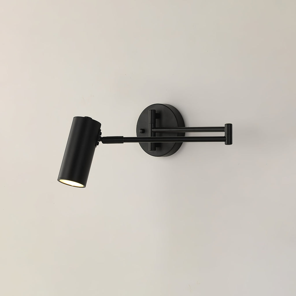 Clérachic wall light in black, with the arm folded and the cylinder head aimed down, on a plain pale wall.