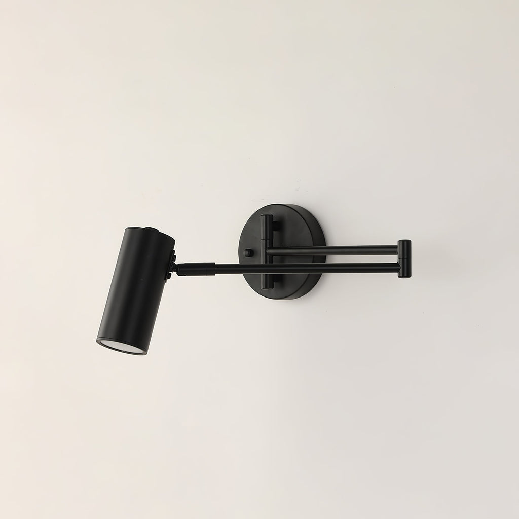 A Clérachic black wall light with a folded arm, on a cream wall, with its head aimed down.