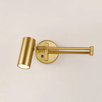 This Clérachic gold wall light with a folding arm and a cylinder head aimed down, on a warm cream wall.