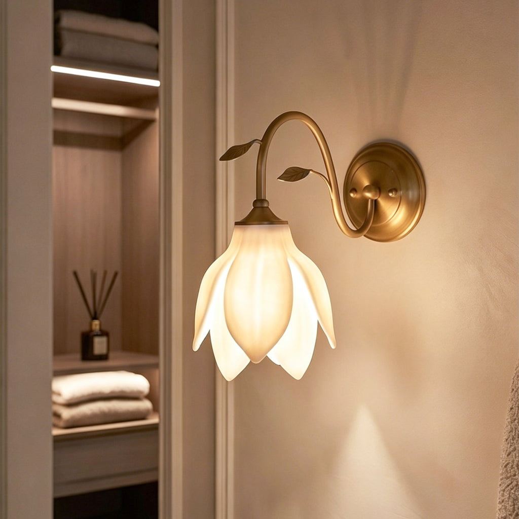This Clérachic wall light with a softly lit petal shade, seen beside an open shelving niche with folded towels and a reed diffuser.