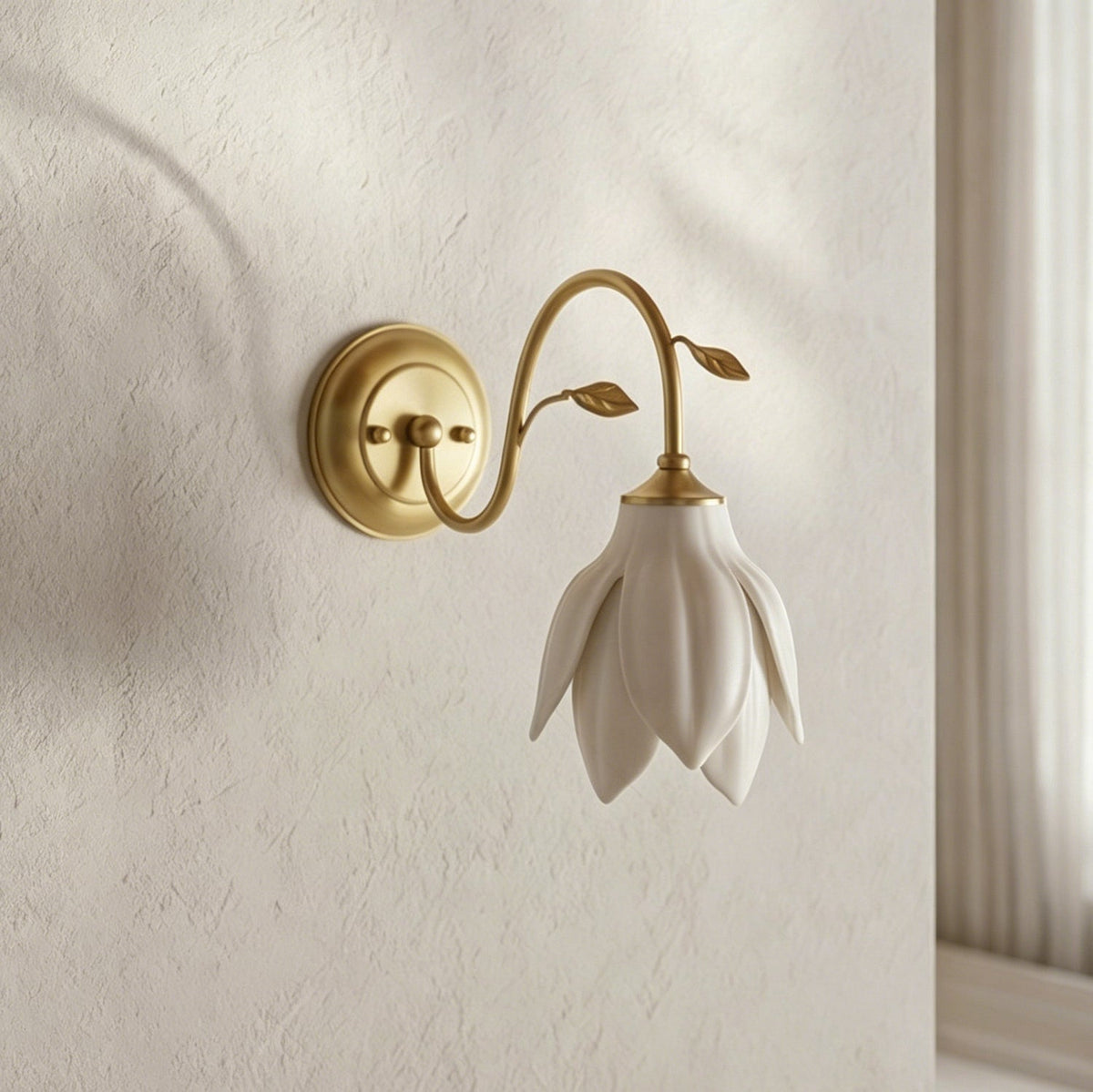 A Clérachic wall light with a white ceramic petal shade hanging down on a curved gold arm, against a textured cream wall.