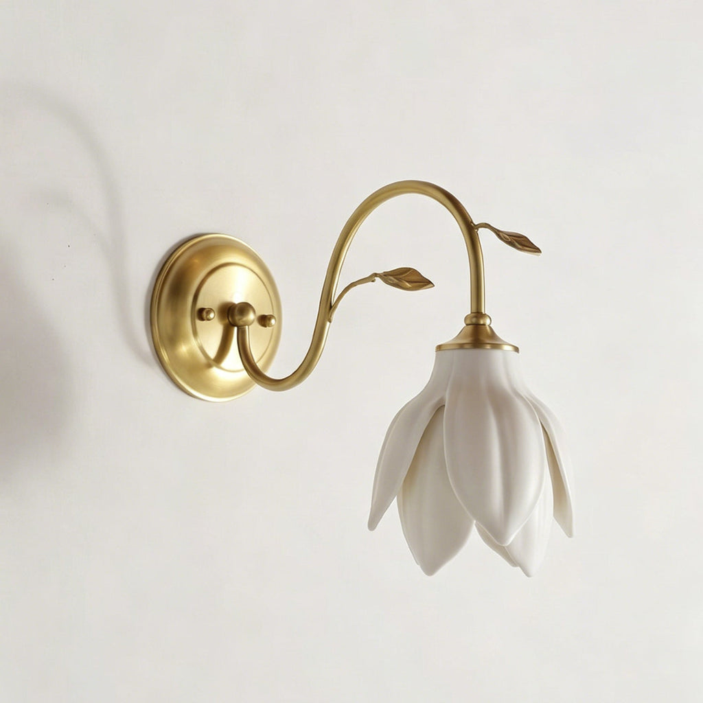 Side-on view of this Clérachic wall light, with the gold round plate, curved arm and white petal shade facing down on a pale wall.