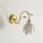 Side-on view of this Clérachic wall light, with the gold round plate, curved arm and white petal shade facing down on a pale wall.
