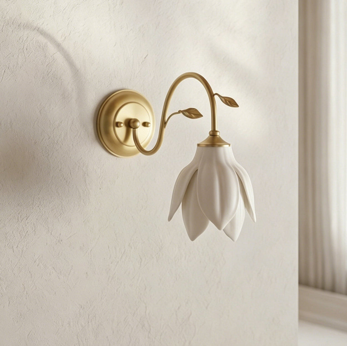Clérachic wall light with a downward petal shade and curved gold arm on a textured cream wall, with a window frame at the right.