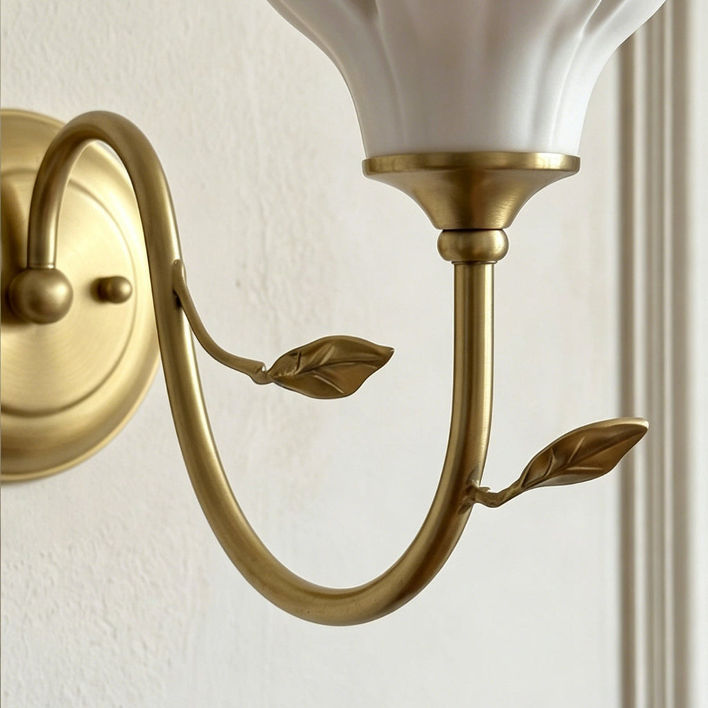 Close view of the gold collar under the shade and the two small leaves on the curved arm of this Clérachic wall light.