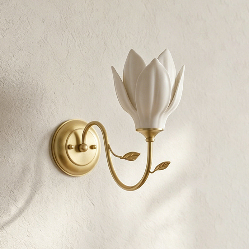 Upward-facing white petal shade on a curved gold arm, this Clérachic wall light shown on a textured cream plaster wall.