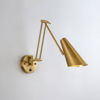 Clérachic gold swing-arm wall light with a conical shade, its folded arm reaching out from a round backplate on a pale grey wall.