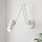 Close view of a white version of the Clérachic wall light, with a cylinder head, gold joints and a round backplate on a white wall.