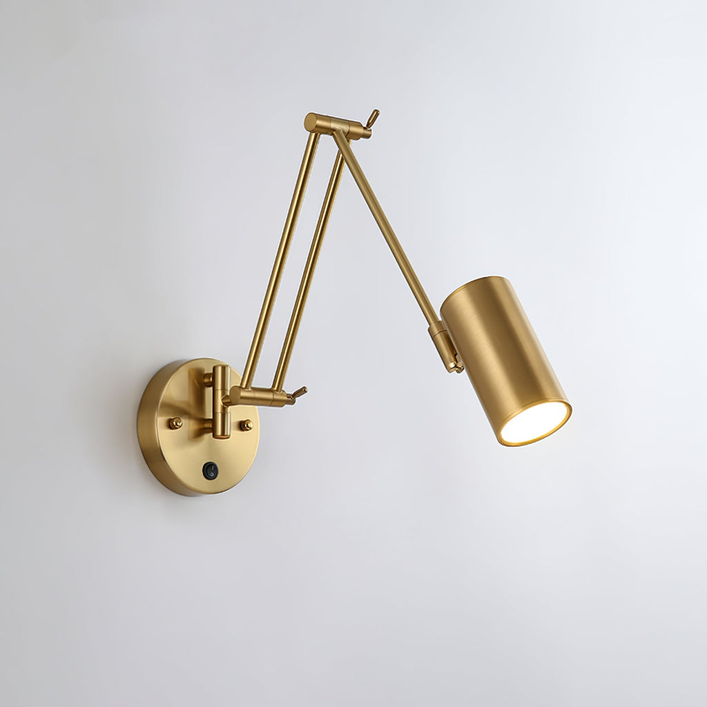 Clérachic gold swing-arm wall light with a cylinder head, the folded arm pointing left from its round backplate, on a pale wall.