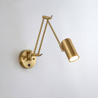 Clérachic gold swing-arm wall light with a cylinder head, the folded arm pointing left from its round backplate, on a pale wall.