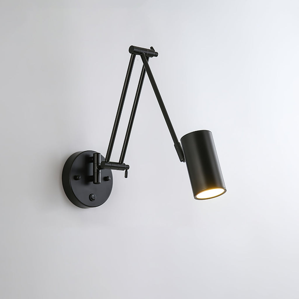 Black Clérachic swing-arm wall light with a cylinder head, its arm reaching right from a round backplate on a pale wall.