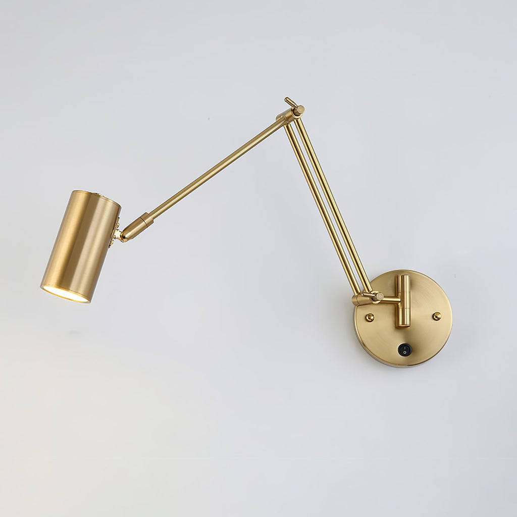 Gold Clérachic swing-arm wall light with a small cylinder head extended to the left on a long arm, against a light wall.
