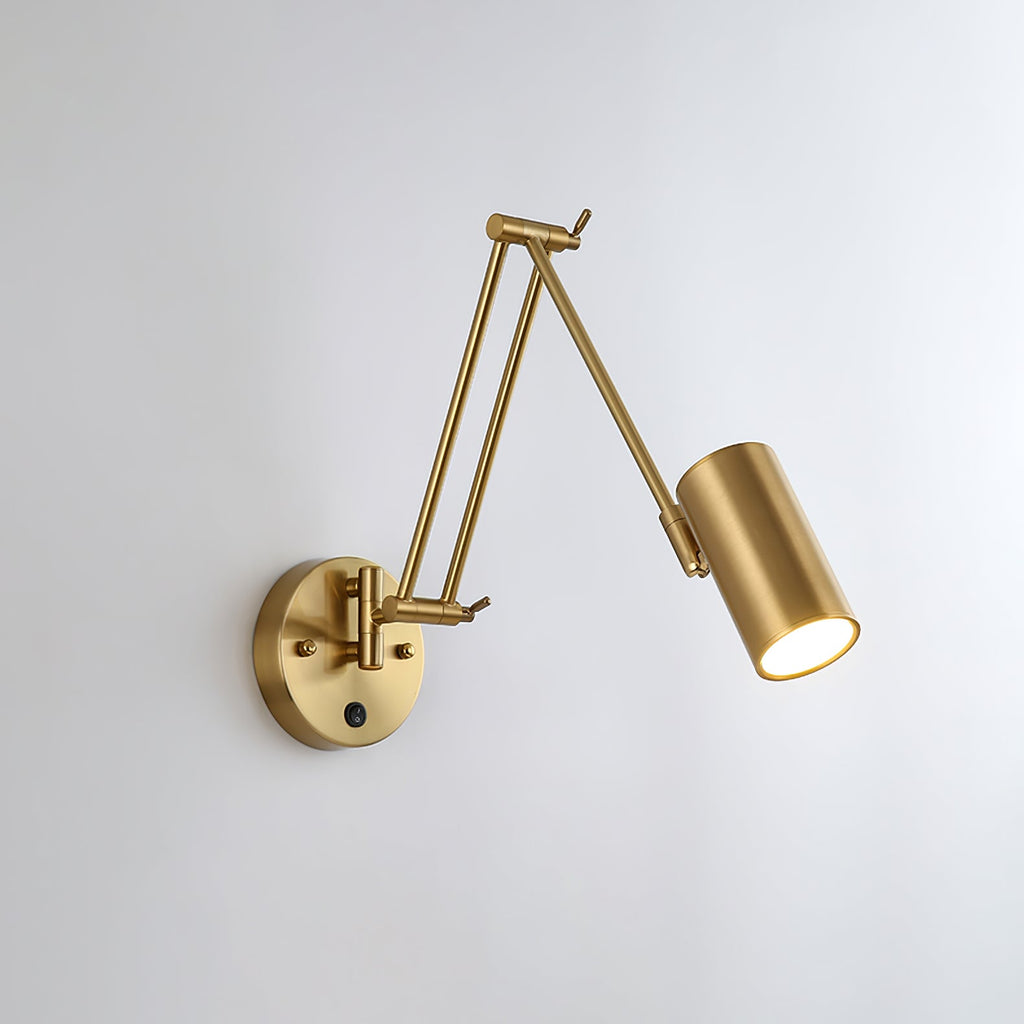 Clérachic gold wall light with a cylinder head angled down to the right on a folded arm, on a pale wall.