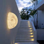 Clérachic half-moon wall light on a white wall beside an outdoor stair with step lights, under an evening sky.