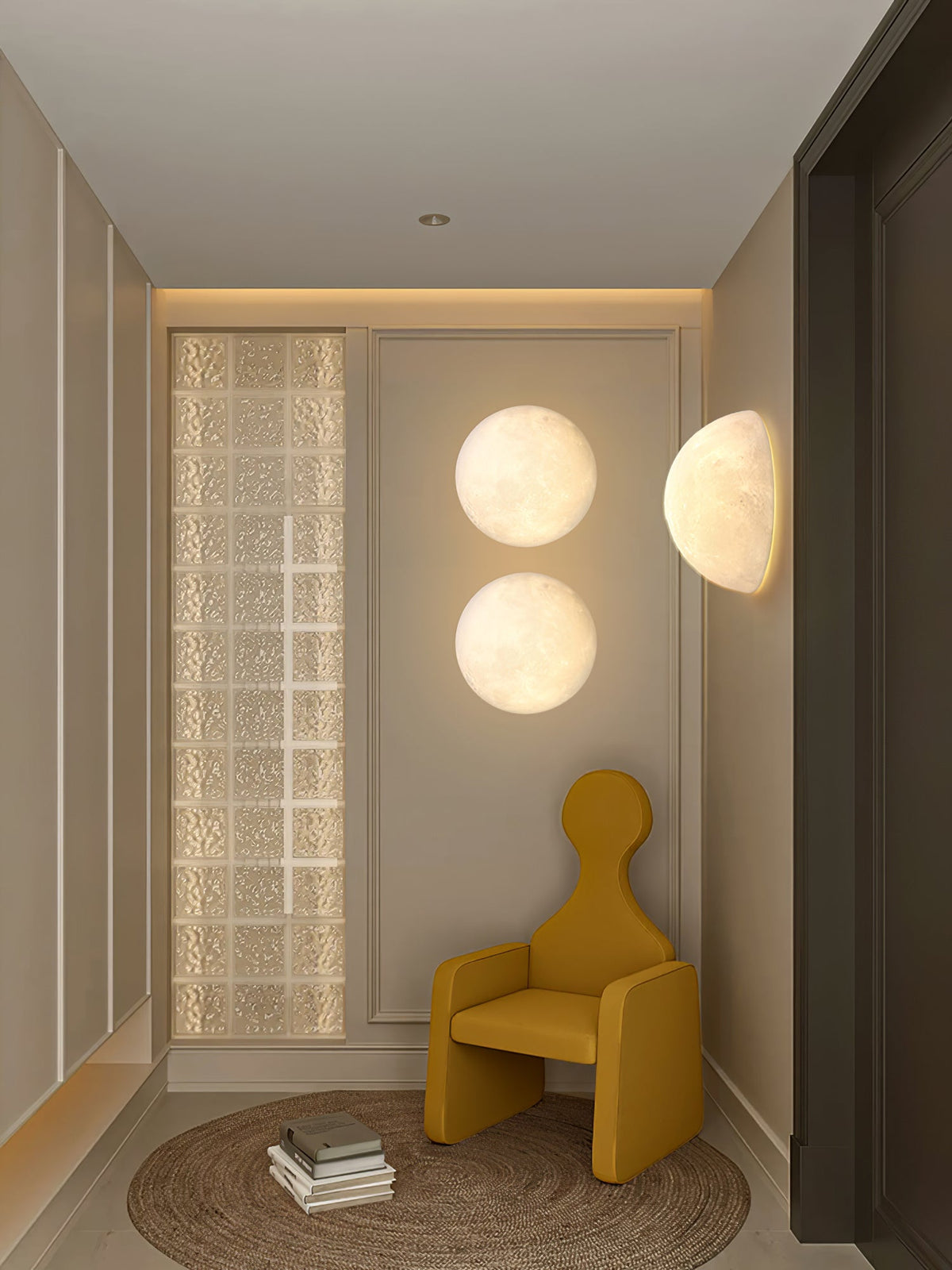 Two round Clérachic moon lights and a half-moon on the walls of a narrow hallway with a mustard armchair and a glass-block panel.
