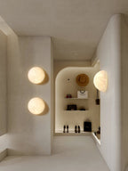 Clérachic moon wall lights in a pale boutique corridor, two round ones and a half-moon beside shelves of shoes.