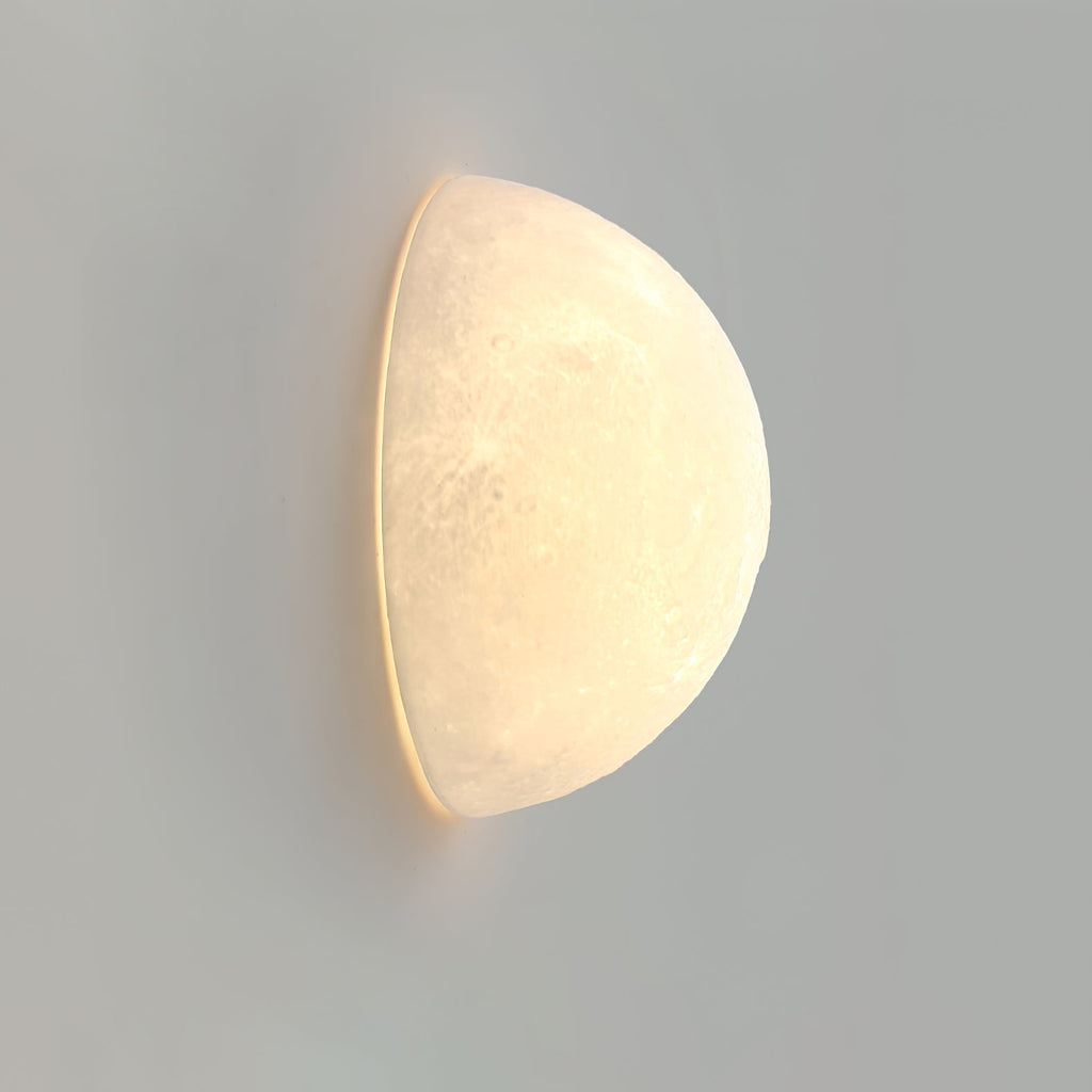 Clérachic half-moon wall light seen from the side, with warm light glowing along its flat edge on a grey wall.