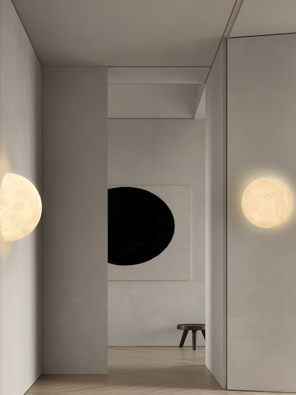 Round Clérachic moon wall light in a plain hallway, with a half-moon on the opposite wall and a dark oval artwork.