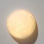 Very close view of a round Clérachic moon wall light, its softly textured surface glowing evenly with a warm tint.