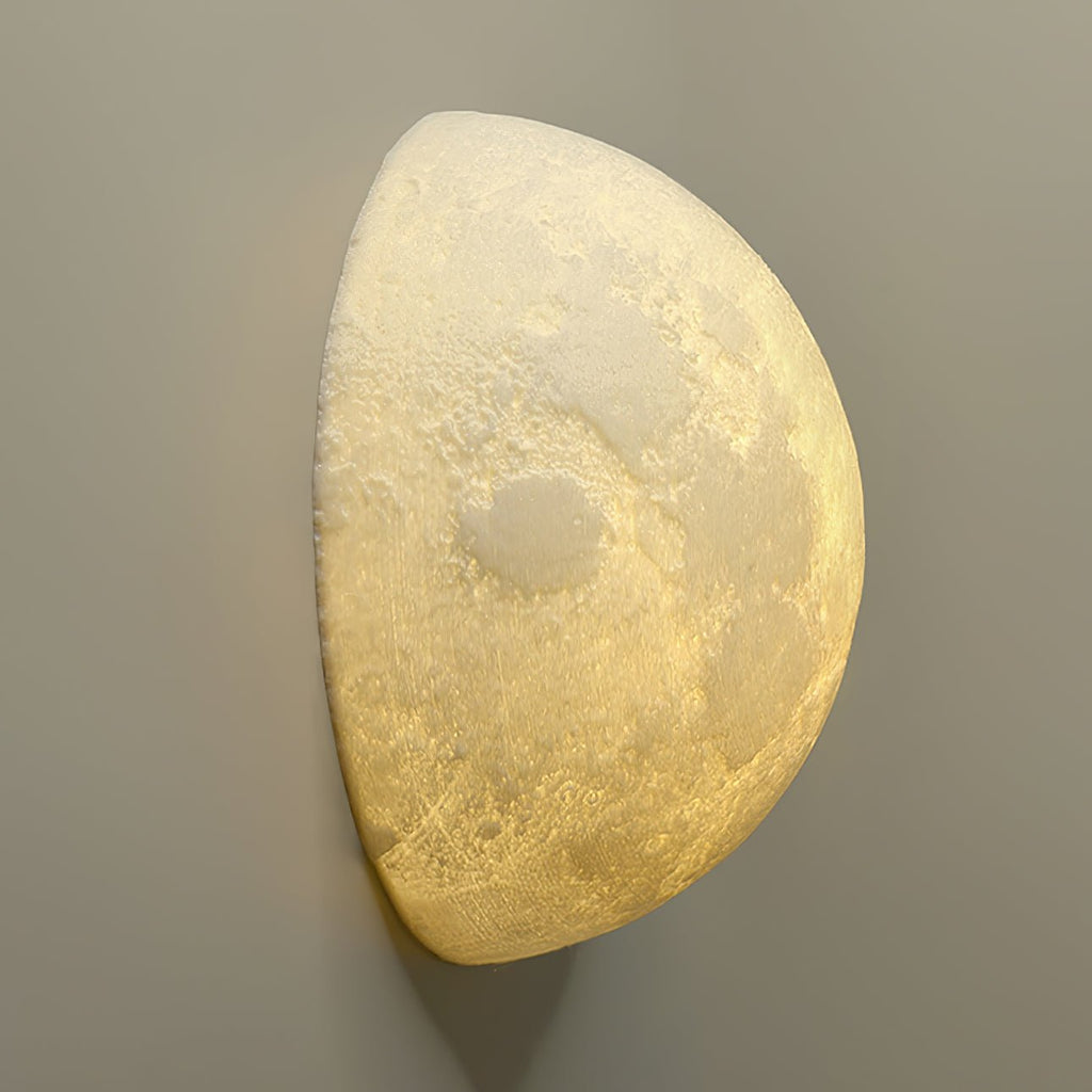 Angled view of a Clérachic half-moon wall light, showing the pitted lunar surface lit from within against a taupe wall.