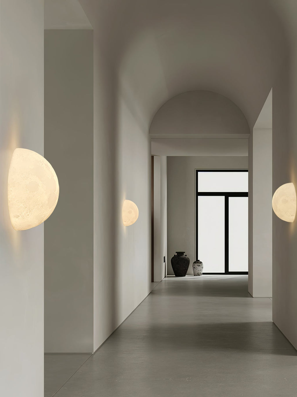 Clérachic half-moon and round moon wall lights along a long, arched white corridor with a glass door at the end.