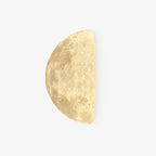 Clérachic half-moon wall light on a white backdrop, with its flat edge on the right and a cratered surface lit warmly.