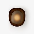 A lit Clérachic wall light with a dark bronze rim around a frosted oval shade, glowing warm in the centre, on a white backdrop.