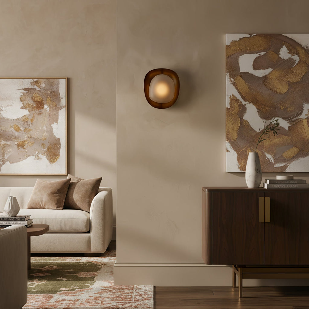 This Clérachic wall light glows softly on a beige wall between two abstract paintings, above a sofa and a dark wood sideboard.