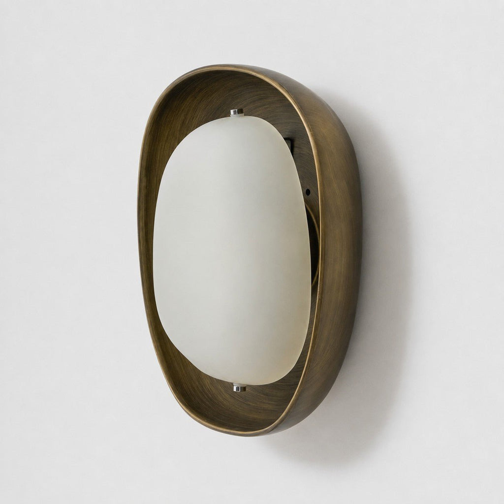 From the side, the deep bronze bowl and domed frosted shade of this Clérachic wall light stand clear of a pale grey wall.