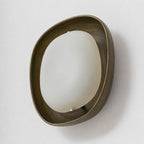Three-quarter view of a Clérachic wall light switched off, with a brushed bronze rim around a creamy white frosted shade.