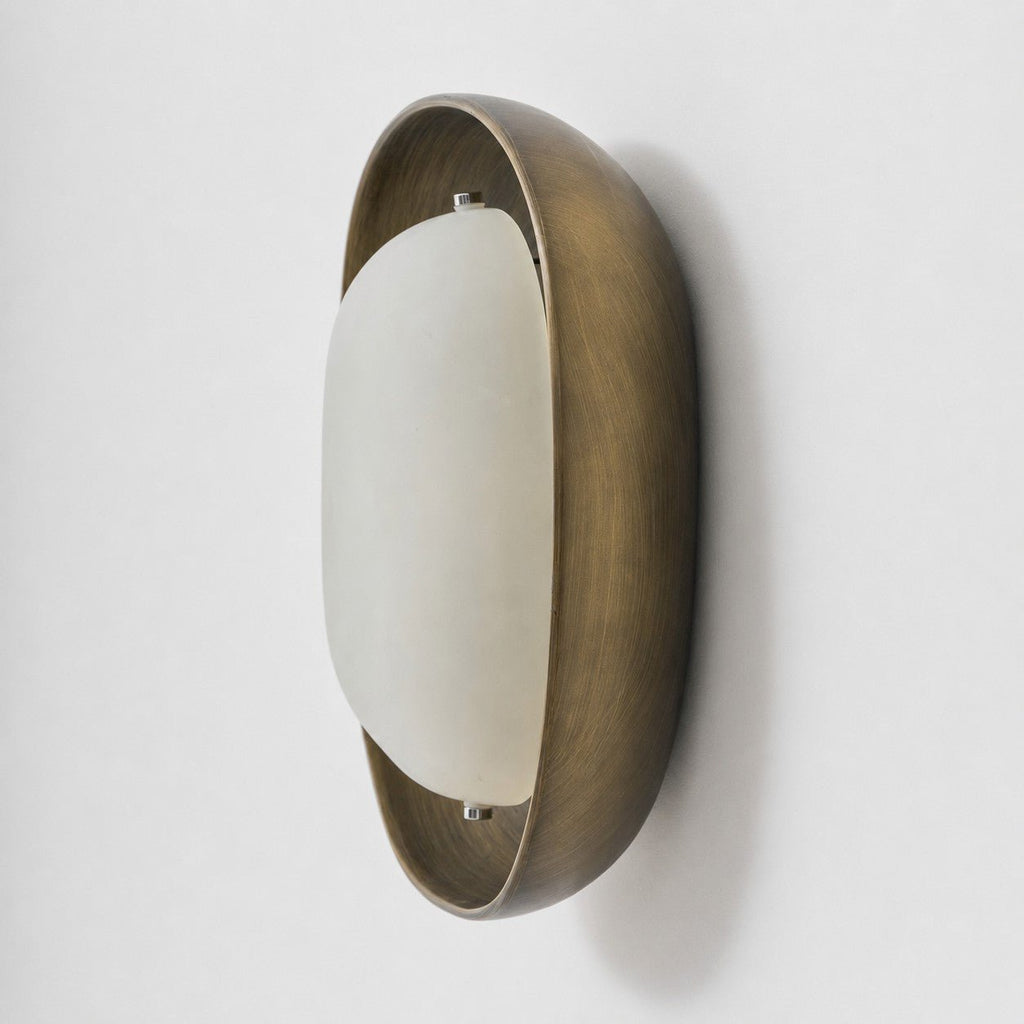 Side view of this Clérachic wall light, with a brushed bronze bowl and a smooth, pale frosted shade set slightly forward.