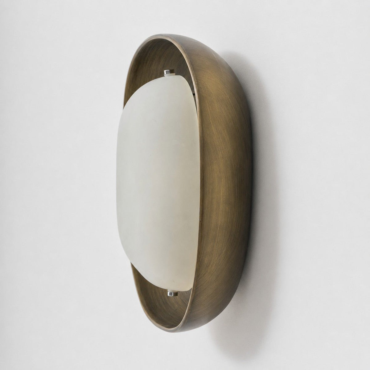 Side view of this Clérachic wall light, with a brushed bronze bowl and a smooth, pale frosted shade set slightly forward.
