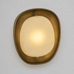A lit Clérachic wall light in front view, with a warm centre glow fading toward the edges of the frosted shade, on grey.