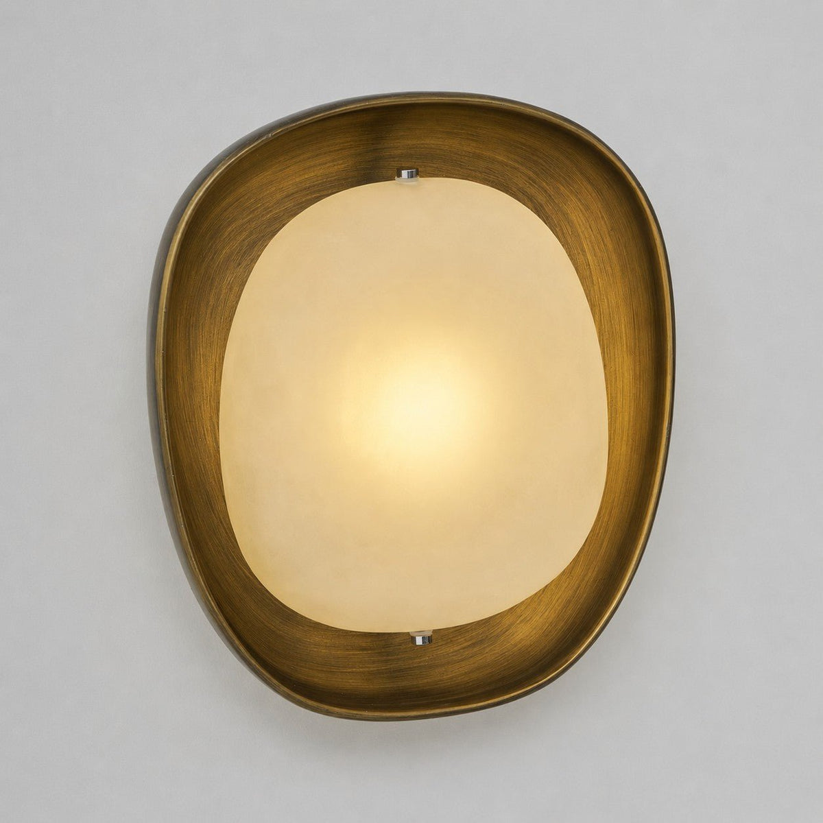 A lit Clérachic wall light in front view, with a warm centre glow fading toward the edges of the frosted shade, on grey.