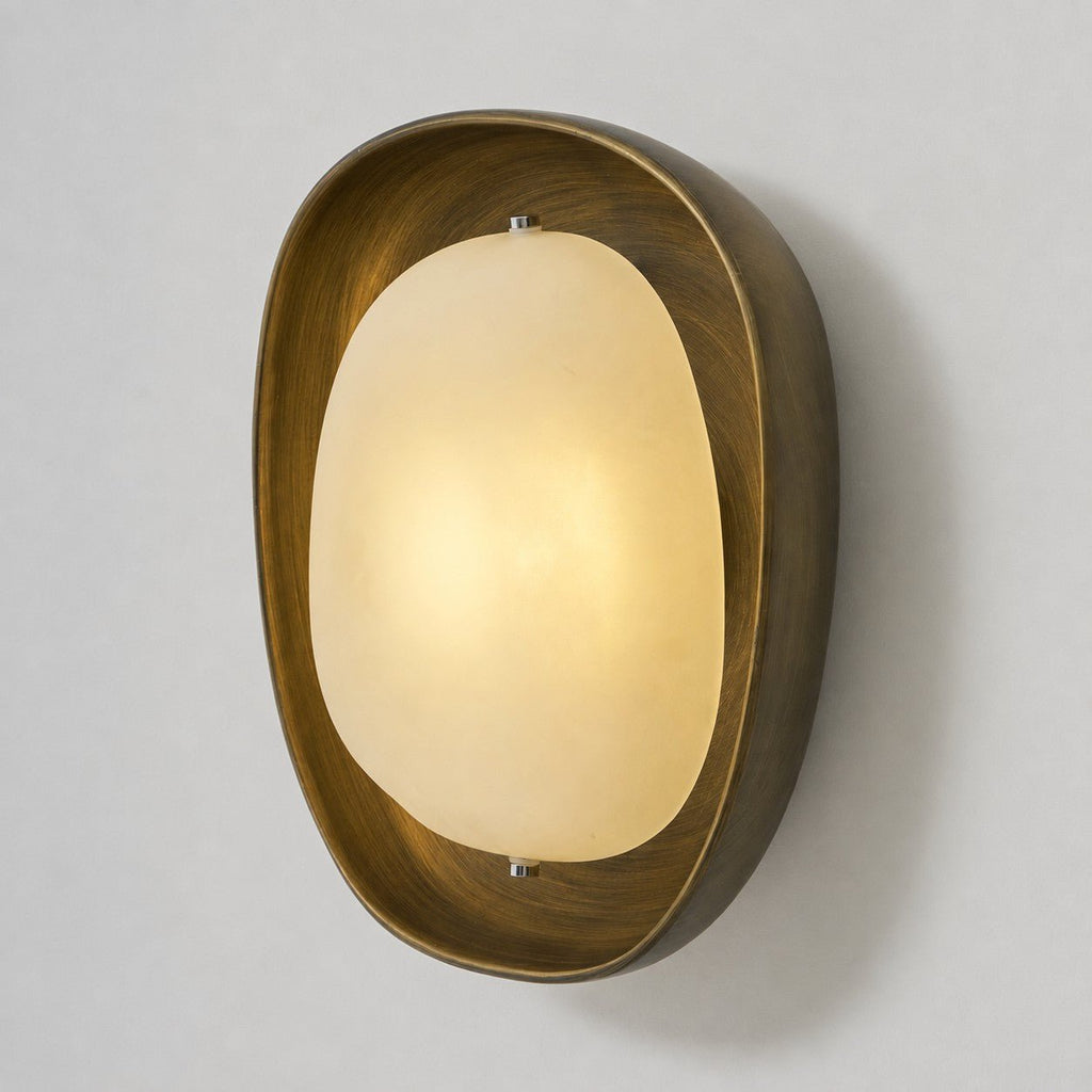 Seen from a slight angle, a lit Clérachic wall light glows warm in its bronze bowl on a plain grey wall.