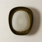 This Clérachic wall light, switched off, shows a cloudy frosted shade in a dark bronze bowl against a cream plaster wall.