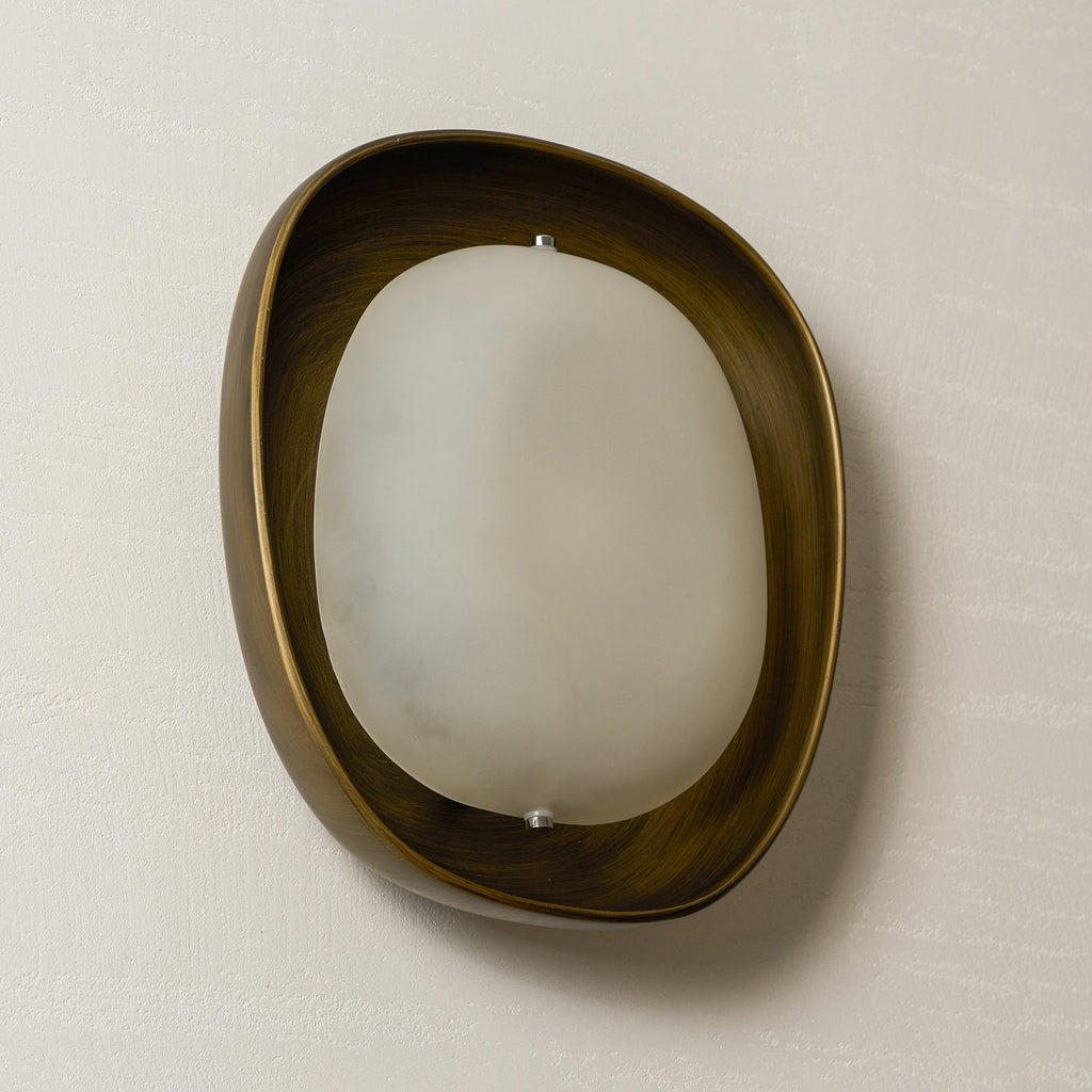 A Clérachic wall light switched off and turned slightly, with soft cloudy glass inside a bronze rim, on a cream wall.
