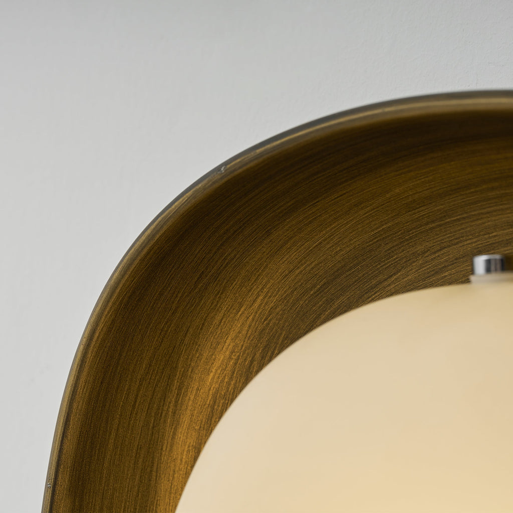 Close view of the brushed bronze bowl and the frosted shade of this Clérachic wall light, with a small metal screw at the top.