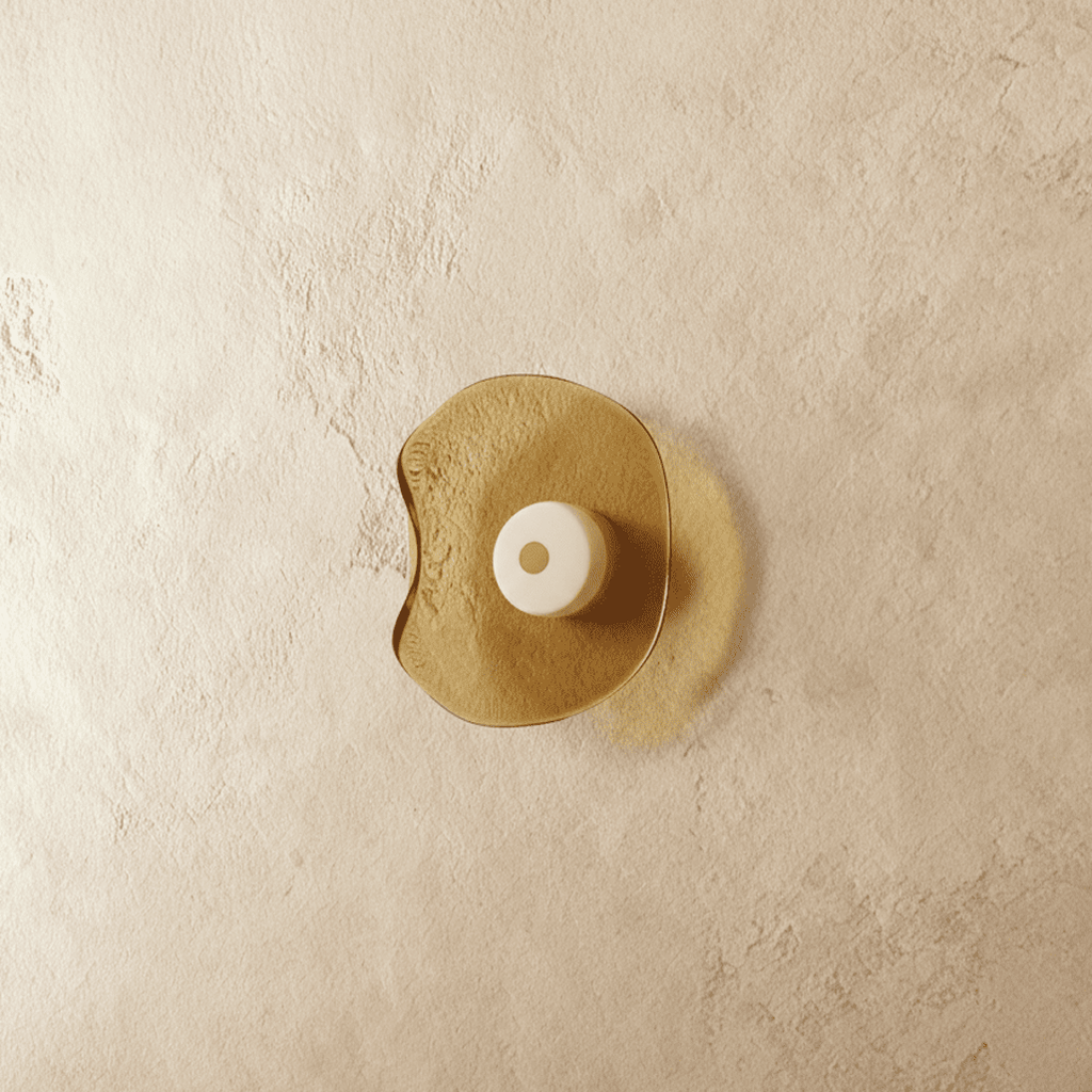Clérachic wall light with a free-form amber glass shade and a cream glass centre disc, shown switched off on limewash.