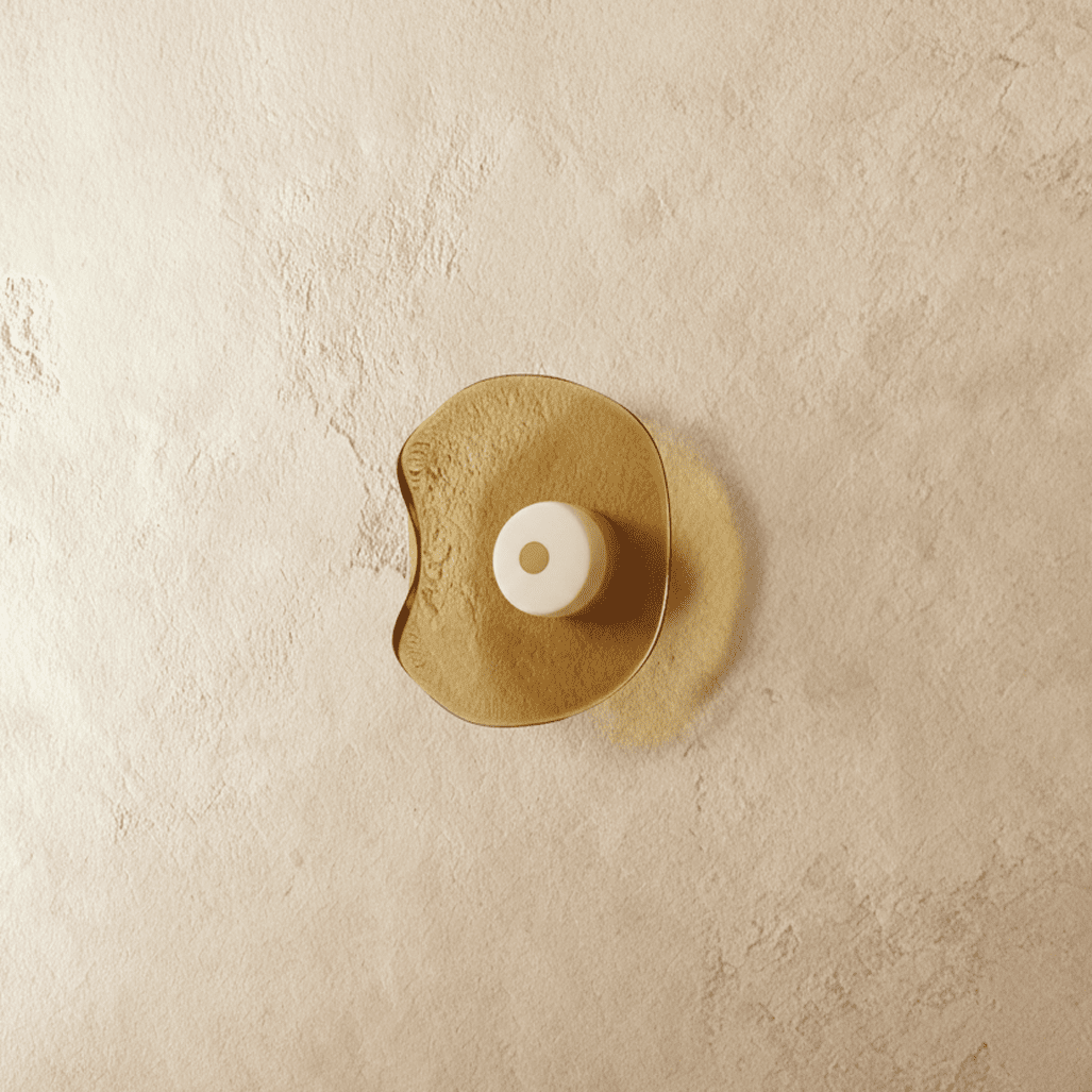 Clérachic wall light with a free-form amber glass shade and a cream glass centre disc, shown switched off on limewash.