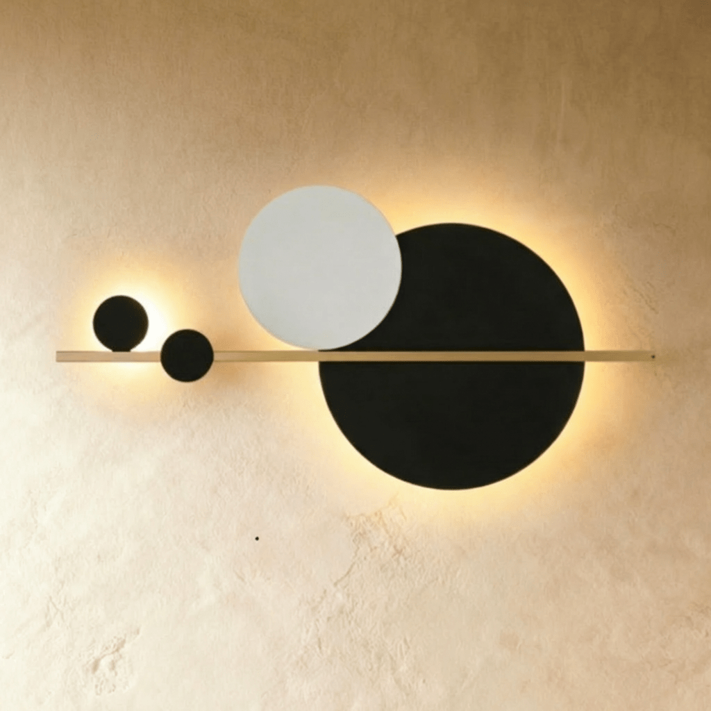 Clérachic black and white disc wall lamp on a slim brass bar, backlit warm white against a limewash wall.