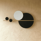 Clérachic black and white disc wall lamp on a slim brass bar, shown unlit on a limewash wall.