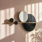 Clérachic black and white disc wall lamp on a brass bar, close up on a blush wall with sunlit window shadows.