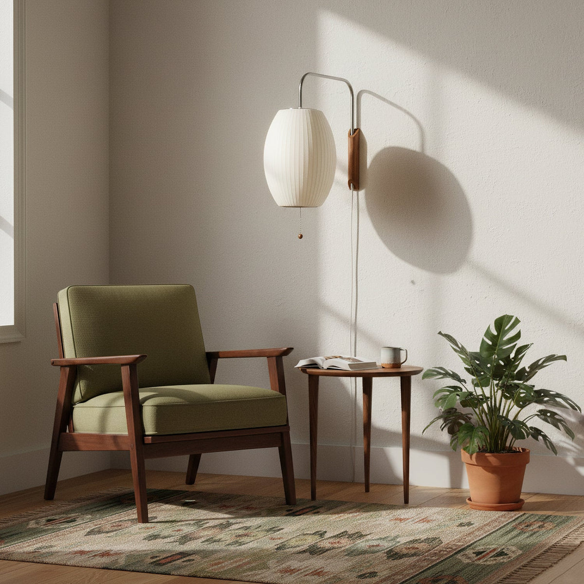 A Clérachic wall light with an oval white shade hangs over a green armchair and small side table, its arm throwing a clear shadow on the wall.