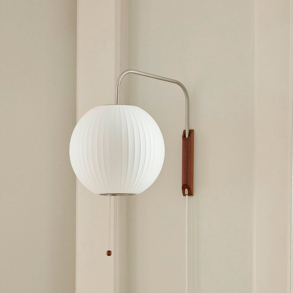 Round white ribbed globe on this Clérachic wall light, with a walnut bracket, steel arm and a pull cord ending in a small wooden bead.