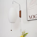 Low-angle view of an unlit oval shade, showing its open base on this Clérachic wall light, with a framed print to the right.