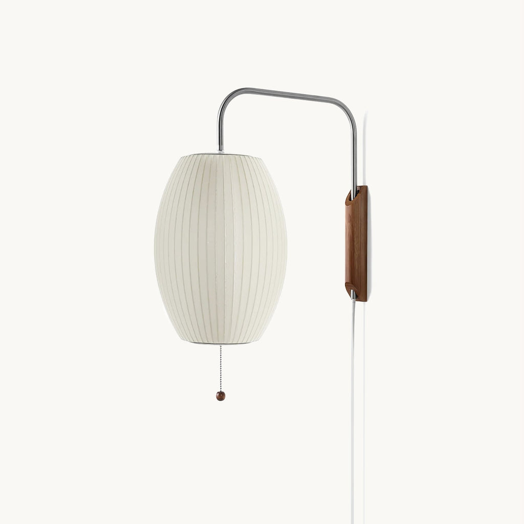 Oval ribbed shade and curved steel arm of this Clérachic wall light on a soft cream backdrop, with a walnut bracket and bead pull.