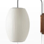 Close view of the fine ribbed texture on the oval shade of this Clérachic wall light, with part of the walnut bracket at the edge.
