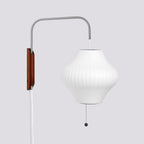 Pear-shaped white shade on a Clérachic wall light, with a rich walnut bracket and bead pull on a soft grey backdrop.